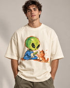 Man in an off-white oversized French terry t-shirt printed with a green alien touching paws with an orange kitten