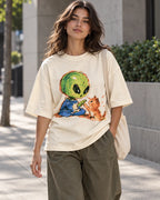 Woman on a street in an off-white oversized French terry t-shirt with a green alien touching paws with an orange kitten