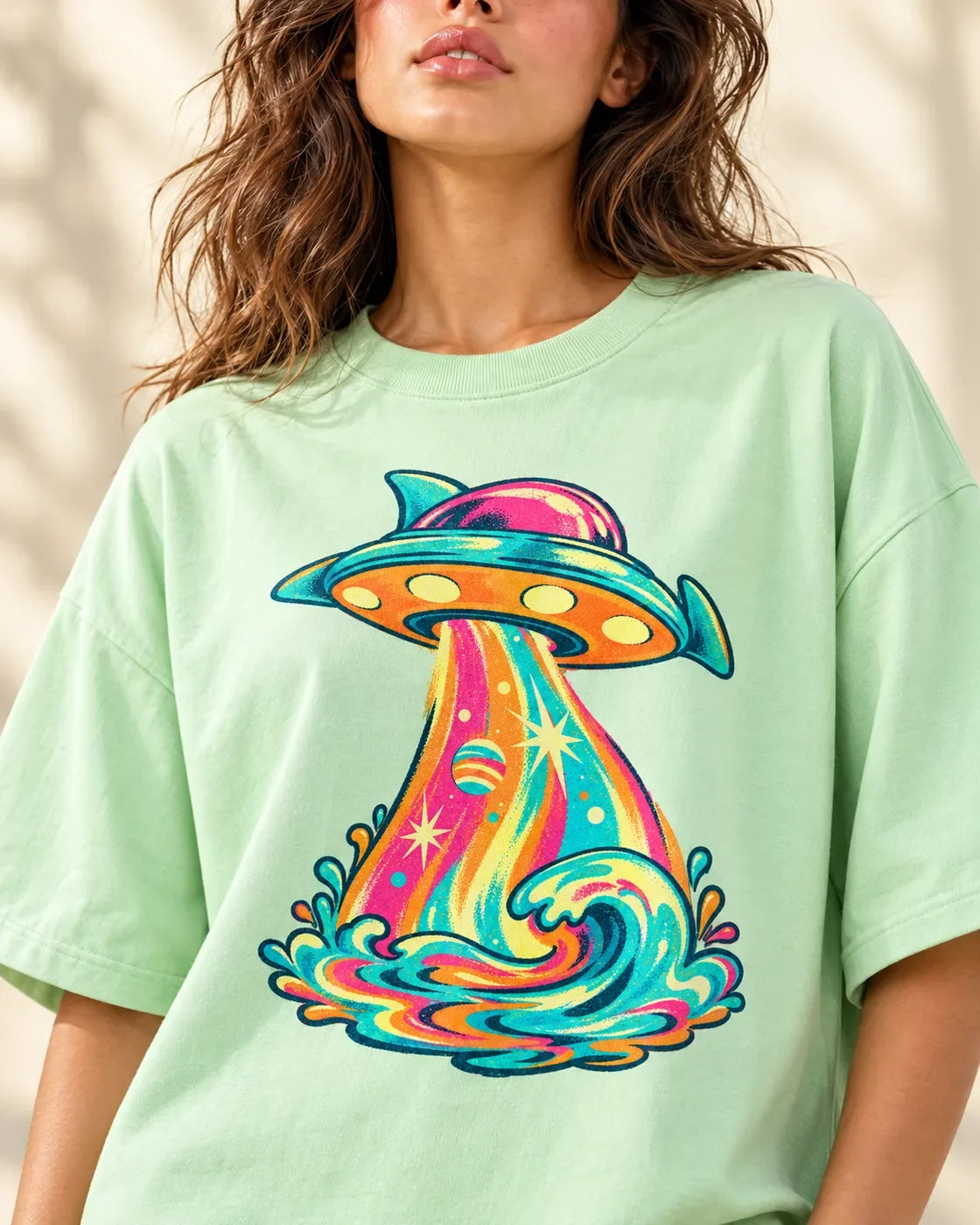 Tropical Transmission print close-up: finned saucer beaming sunset swirls into a turquoise wave on jade French terry