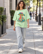 Woman walking down a city street in the Tropical Transmission jade French terry oversized tee
