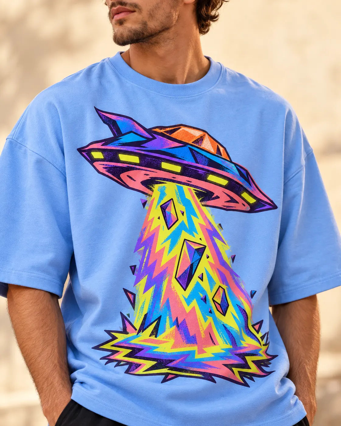 Angled close-up of the Arcade Anomaly UFO print on a baby blue French terry tee