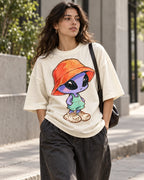Woman on a street in an off-white oversized French terry t-shirt with a purple alien in a bucket hat, overalls and sneakers
