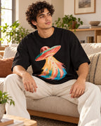Man relaxing on a couch in the Peach Mirage UFO oversized tee, black