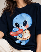 Close-up of a blue alien in a sweater hugging a small red UFO printed on a navy blue oversized French terry t-shirt