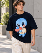 Man on a street in a navy blue oversized French terry t-shirt with a blue alien in a sweater hugging a small red UFO