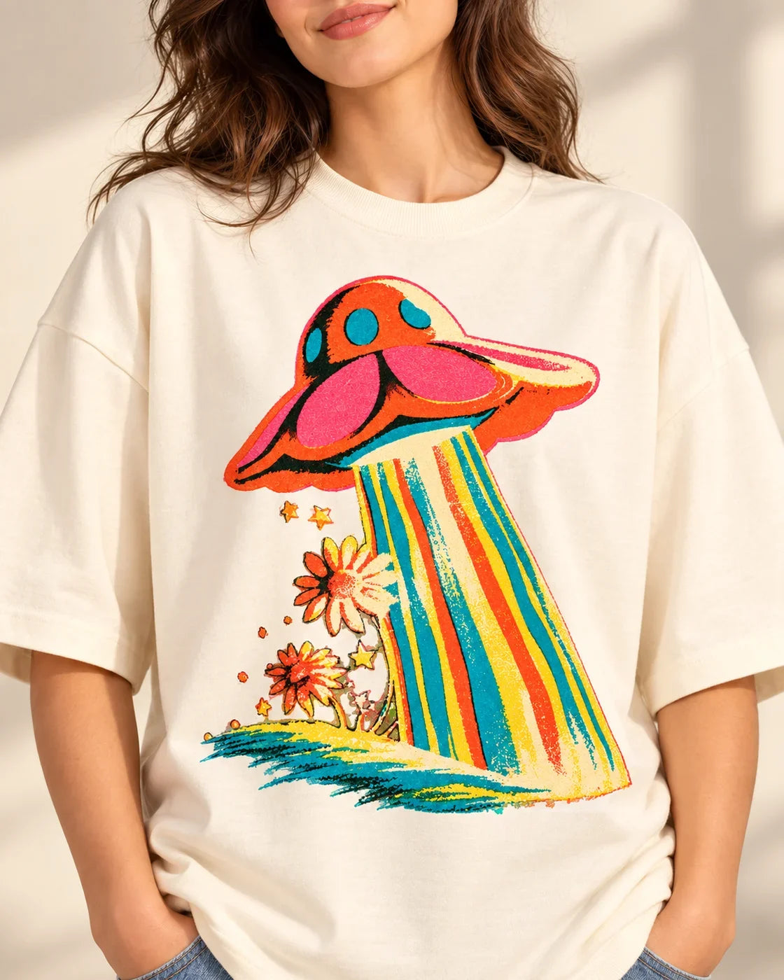Cosmic Garden print close-up: coral saucer beaming rainbow stripes over orange daisies on off-white French terry