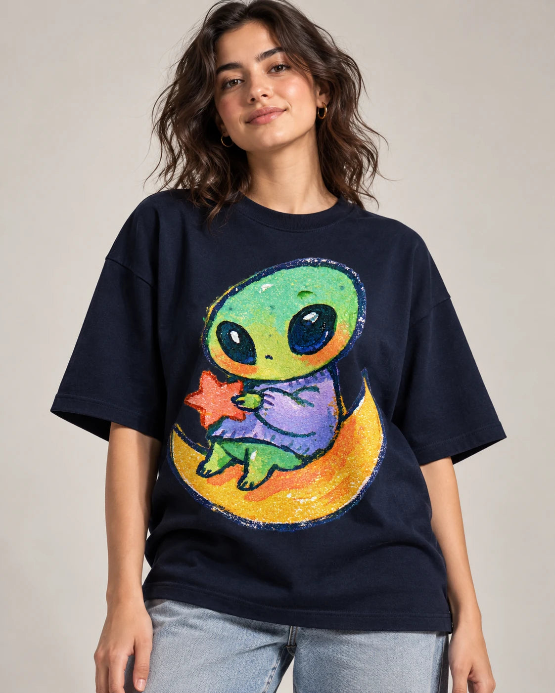 Woman in a navy blue oversized French terry t-shirt printed with a green alien hugging a red star on a crescent moon