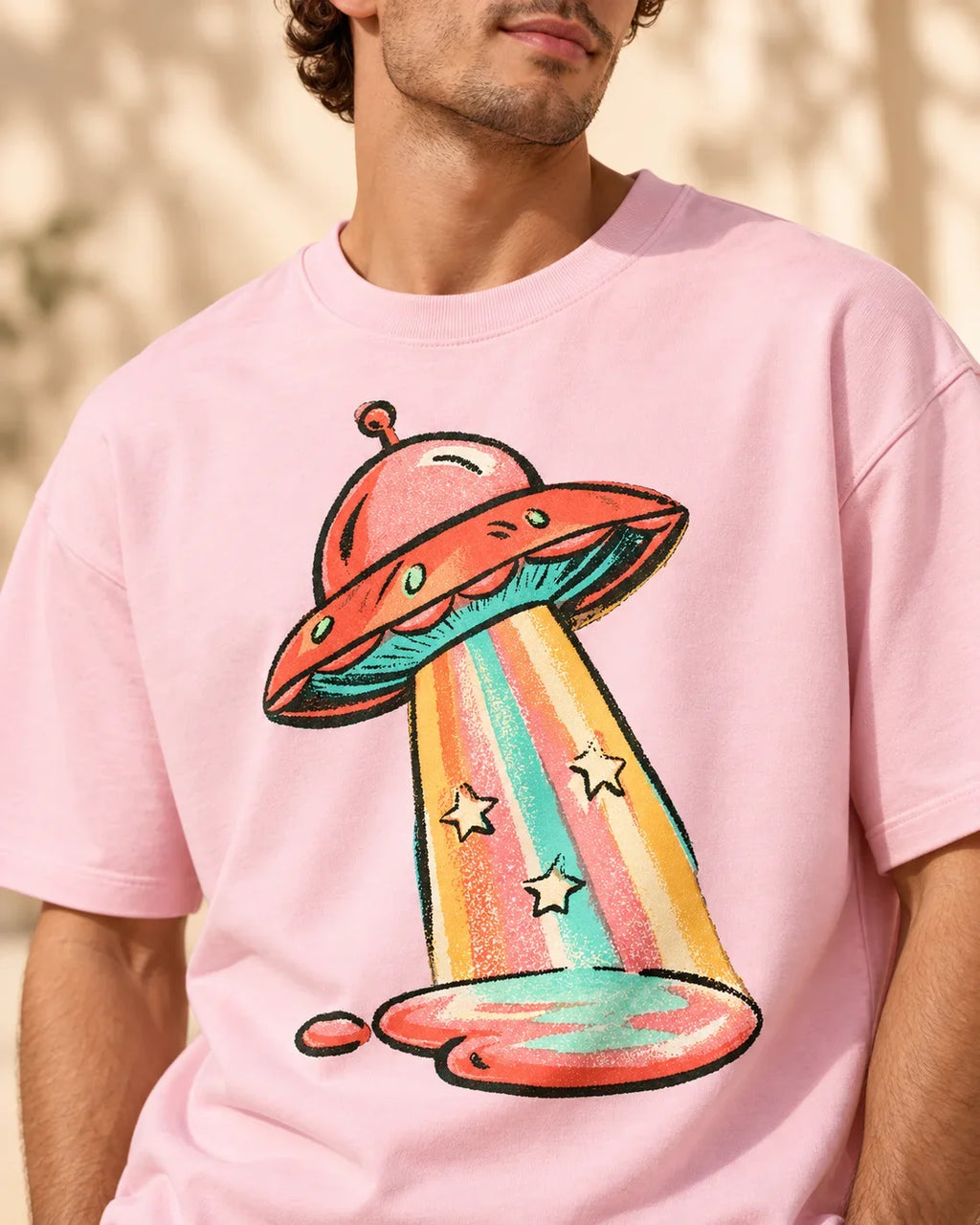 Angled close-up of the Candy Orbit UFO print on a light baby pink French terry tee