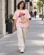 Woman walking down a city street in the Candy Orbit light baby pink French terry oversized tee