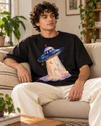 Man relaxing on a couch in the Lunar Haze UFO oversized tee, black