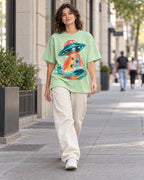 Woman walking down a city street in the Tidal Transit jade French terry oversized tee