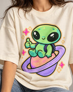 Close-up of a green alien giving a thumbs-up on a ringed planet printed on an off-white oversized French terry t-shirt
