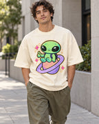 Man on a street in an off-white oversized French terry t-shirt with a green alien giving a thumbs-up on a ringed planet