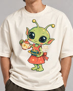 Close-up of a green alien in an apron pouring tea from a teapot printed on an off-white oversized French terry t-shirt