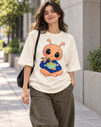 Woman on a street in an off-white oversized French terry t-shirt with a peach alien eating noodles from a ringed bowl