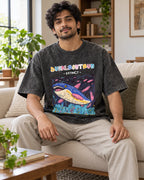Model wearing the Dunkleosteus black acid wash oversized T-shirt seated on a sofa, Fourth Dimension Club