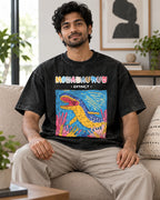 Model wearing the Mosasaurus black acid wash oversized T-shirt seated on a sofa, Fourth Dimension Club
