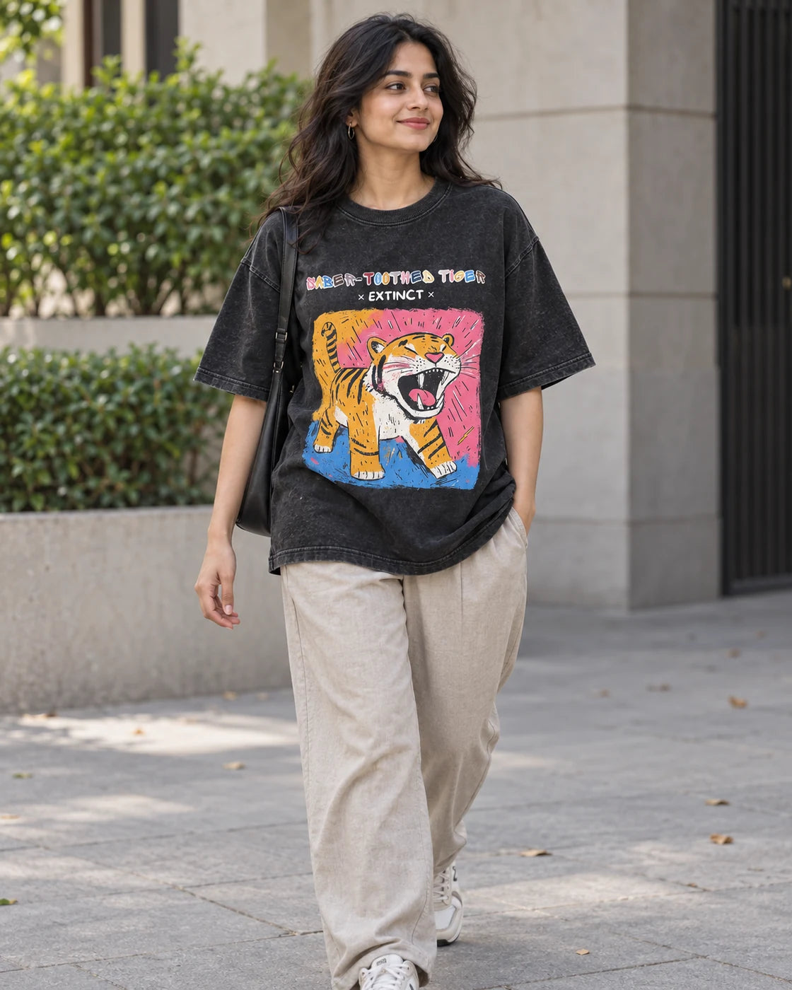 Model wearing the Saber-toothed Tiger black acid wash oversized T-shirt on a city street, Fourth Dimension Club