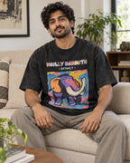 Model wearing the Woolly Mammoth black acid wash oversized T-shirt seated on a sofa, Fourth Dimension Club