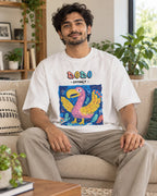 Model wearing the Dodo white oversized French terry T-shirt seated on a sofa, Fourth Dimension Club