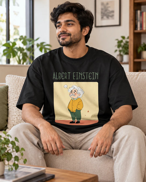 Model wearing the Albert Einstein Genius Doodles oversized French terry T-shirt by Fourth Dimension Club, seated on a sofa