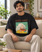Model wearing the Antonio Vivaldi Genius Doodles oversized French terry T-shirt by Fourth Dimension Club, seated on a sofa