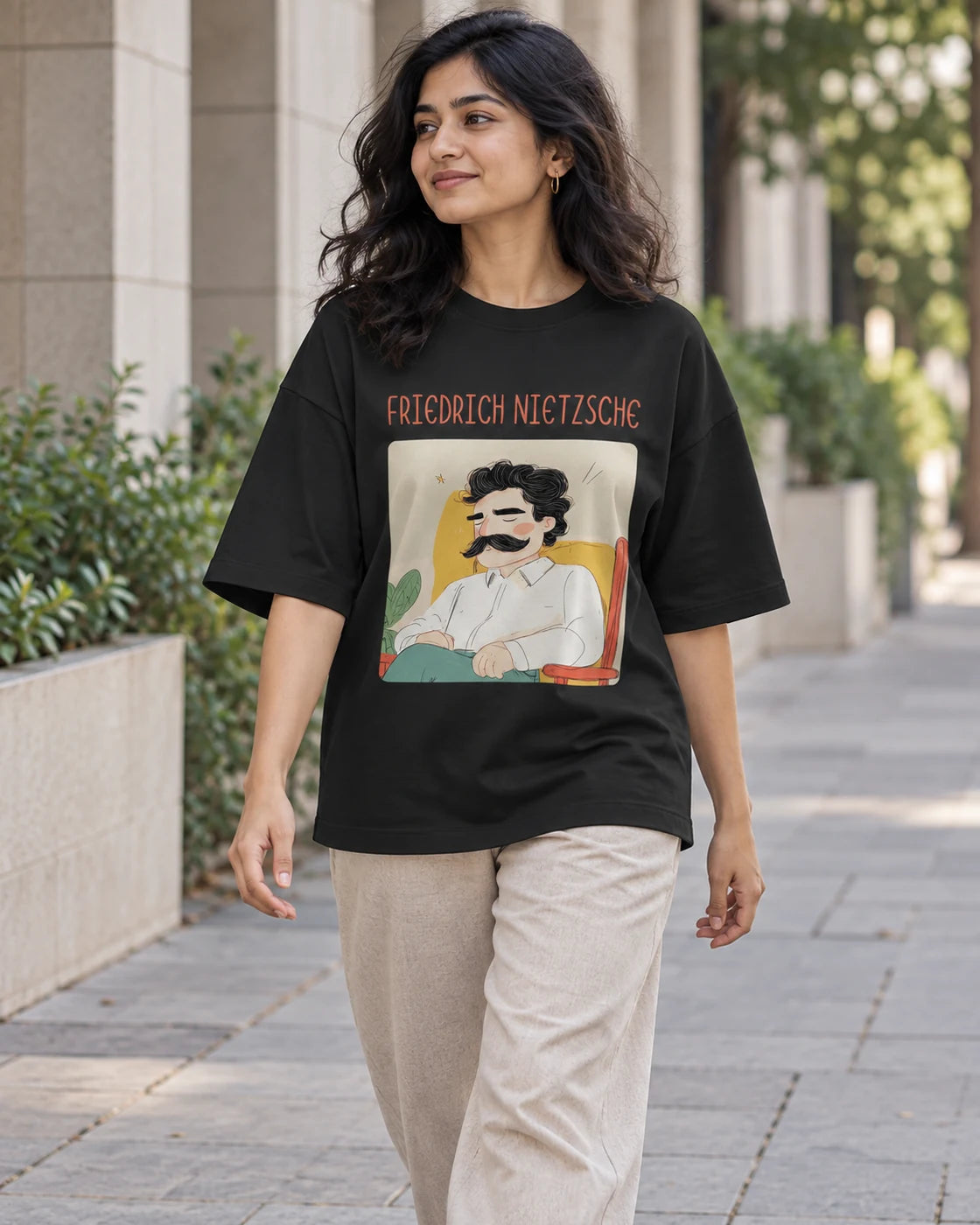 Model wearing the Friedrich Nietzsche Genius Doodles oversized French terry T-shirt by Fourth Dimension Club on a city street