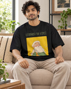 Model wearing the Leonardo da Vinci Genius Doodles oversized French terry T-shirt by Fourth Dimension Club, seated on a sofa