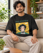 Model wearing the Ludwig van Beethoven Genius Doodles oversized French terry T-shirt by Fourth Dimension Club, seated on a sofa