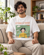 Model wearing the Richard Feynman Genius Doodles oversized French terry T-shirt by Fourth Dimension Club, seated on a sofa