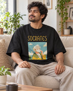 Model wearing the Socrates Genius Doodles oversized French terry T-shirt by Fourth Dimension Club, seated on a sofa