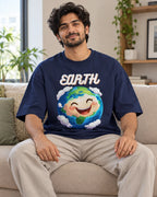 Model wearing the Earth Stellar Squad oversized French terry T-shirt in navy blue by Fourth Dimension Club, seated on a sofa