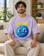 Model wearing the Neptune Stellar Squad oversized French terry T-shirt in lavender by Fourth Dimension Club, seated on a sofa