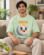 Model wearing the Pluto Stellar Squad oversized French terry T-shirt in jade by Fourth Dimension Club, seated on a sofa