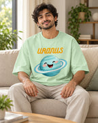 Model wearing the Uranus Stellar Squad oversized French terry T-shirt in jade by Fourth Dimension Club, seated on a sofa